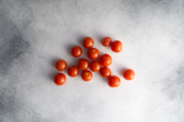 Cherry tomatoes scattered across white textured stone concrete table, top view with copy space. Ingredients for cooking.