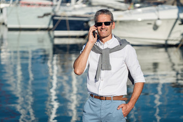 Senior man talking on the smartphone on the marina