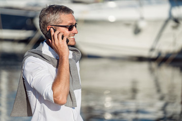 Senior man talking on the smartphone on the marina