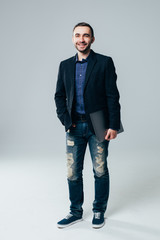 Handsome businessman smiling to camera with a gray laptop in his hand, isolated on white background