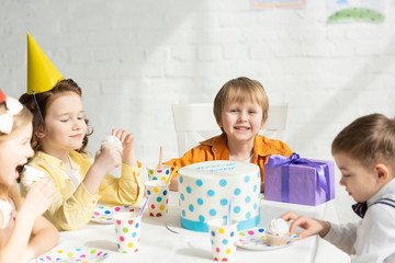 Wall Mural - adorable kids sitting at table with cake during birthday party celebration