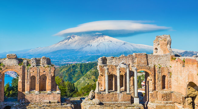 ancient greek theatre in taormina on background of etna volcano, sicily, italy.