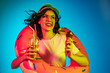 © master1305 - Happy young woman in a rubber ring with an icecream and drink on trendy blue neon studio background. Female portrait. Concept of human emotions, facial expression, summer holidays or weekend.