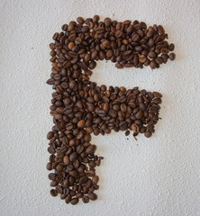 Image of roasted coffee beans shaped alphabet on a white background