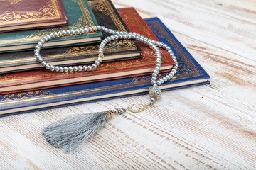 Wall Mural - Holy Quran with arabic calligraphy meaning of Al Quran and tasbih or rosary beads over on wooden table. Selective focus and crop fragment.