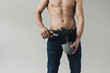 Partial view of shirtless man in jeans cutting plant with secateurs isolated on grey