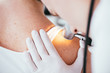 cropped view of dermatologist holding dermatoscope while examining woman with melanoma