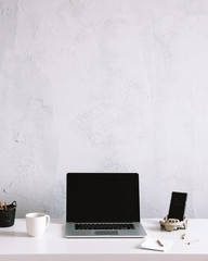 business work table with laptop and phone. office desk on grey wall, with copy space