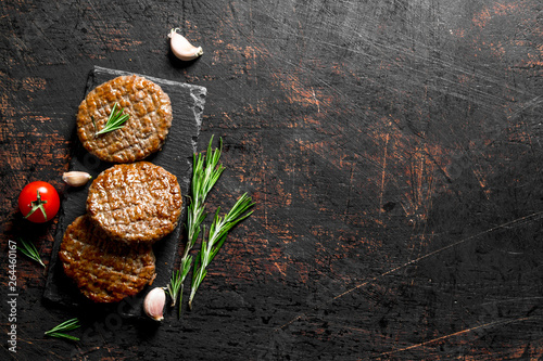 Cutlets on a black stone Board with pieces of garlic,rosemary and cherry Canvas