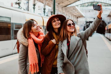 A group of young friends taking a selfie while waiting for their train to leave at the Oporto station in Portugal. Travel photography. Lifestyle