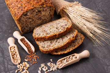 Loaf of wholegrain bread for breakfast, ingredients for baking and ears of rye or wheat grain