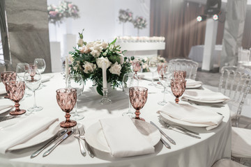 Wall Mural - Wine glasses on round Banquet table served. Interior of restaurant for wedding dinner, ready for guests. Decorated with floral arrangement. Dishes, wine glasses and napkins. Catering concept.