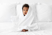 Black Baby Sitting On Bed Wrapped In Towel After Bath