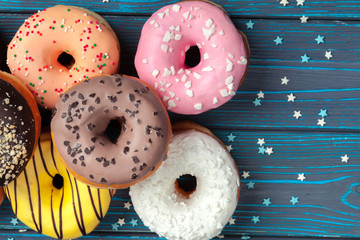 Poster - Colorful fresh donuts on dark blue wooden surface