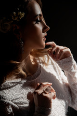 Wall Mural - Close-up portrait of girl with blond hair and hands near the face. Bride with beautiful makeup on a dark background