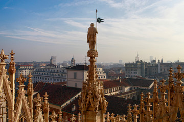 Cathedral statue of the Duomo di Milano towers against the sky above the city