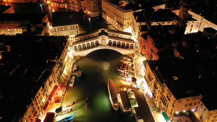 Aerial night shot of iconic illuminated Ponte Rialto or Rialto bridge crossing Grand Canal, Venice, Italy