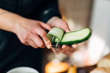 Female chef peeling skin of a cucumber