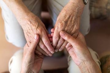 Wall Mural - Nurse consoling her elderly patient by holding her hands