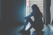 © TeTe Song - Silhouette of girl sitting alone in the dark,Sad and Serious women sitting hug his knee alone of old condo, Domestic violence, family problems, Stress, violence, The concept of depression and suicide.