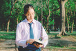 © TeTe Song - Lovely teenage girl wearing school uniform reading book while sitting on a swing at the park .