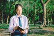 © TeTe Song - Lovely teenage girl wearing school uniform reading book while sitting on a swing at the park .