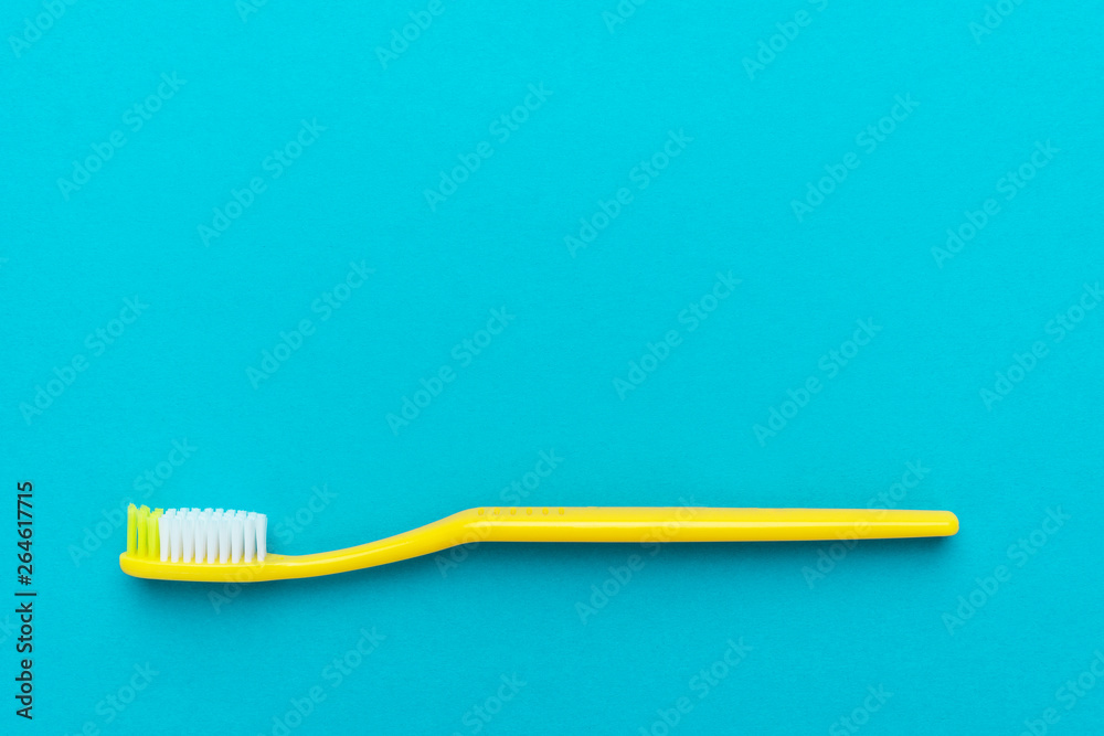 minimalist flat lay photo of yellow toothbrush over turquoise blue background
