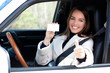 © Nobilior - Beautiful young girl sitting in white car showing an empty white card and thumbs up hand sign