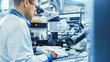 © Gorodenkoff - Electronics Factory Worker in White Work Coat is Soldering a Printed Circuit Board Through a Digital Microscope. High Tech Factory Facility.