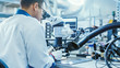© Gorodenkoff - Electronics Factory Worker in White Work Coat is Soldering a Printed Circuit Board Through a Digital Microscope. High Tech Factory Facility.