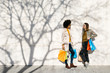 © Westend61 - Two happy women with shopping bags standing at a wall talking