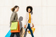 © Westend61 - Two happy women with shopping bags walking along a wall