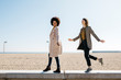 © Westend61 - Two happy friends walking on the promenade enjoying leisure time