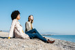 © Westend61 - Two friends sitting on the beach enjoying leisure time