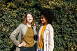 © Westend61 - Portrait of two happy women in front of a hedge