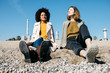 © Westend61 - Two friends sitting on the beach enjoying leisure time