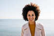 © Westend61 - Portrait of smiling woman with the sea in background