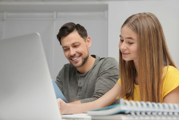 Wall Mural - Father helping his teenager daughter with homework indoors