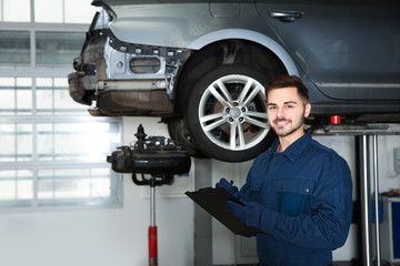 Canvas Print - Technician checking car on hydraulic lift at automobile repair shop