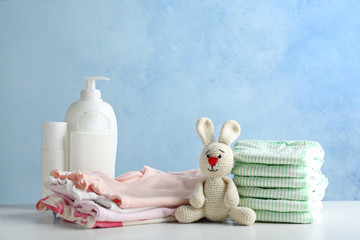 Wall Mural - stack of diapers and baby accessories on table against color background. space for text