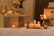 © New Africa - Cosmetics and burning candles on massage table in spa salon, space for text