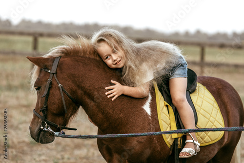 Fotografía Adorable little girl riding a pony at summer