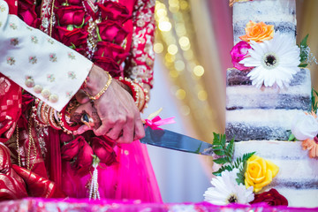 Indian hindu couple's cutting a wedding cake close up