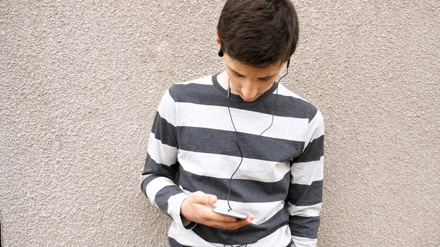 teen boy with smart phone listening or talking on british street. teenager and social media concept