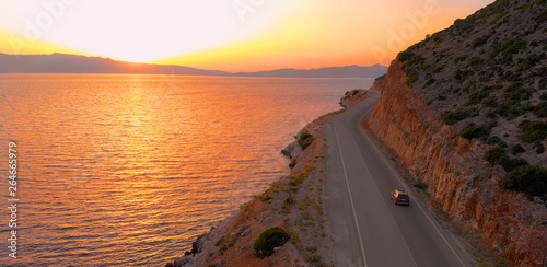 Fotografía DRONE: Flying behind tourist car driving down empty road leading around island