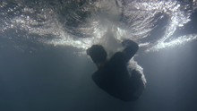 A Man In Clothes Falls Back Into The Water. Underwater Shooting Of A Drowning Man