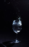 Fototapeta Paryż - Transparent glass of water in the foreground on a black background