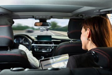 Businesswoman Sitting Inside Car Examining Graph On Laptop