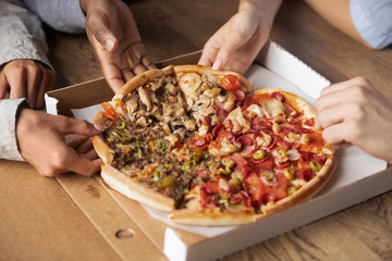 Multiracial hungry people sharing pizza slices hands close up