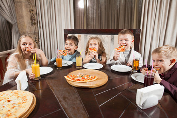 children eat pizza in a restaurant.